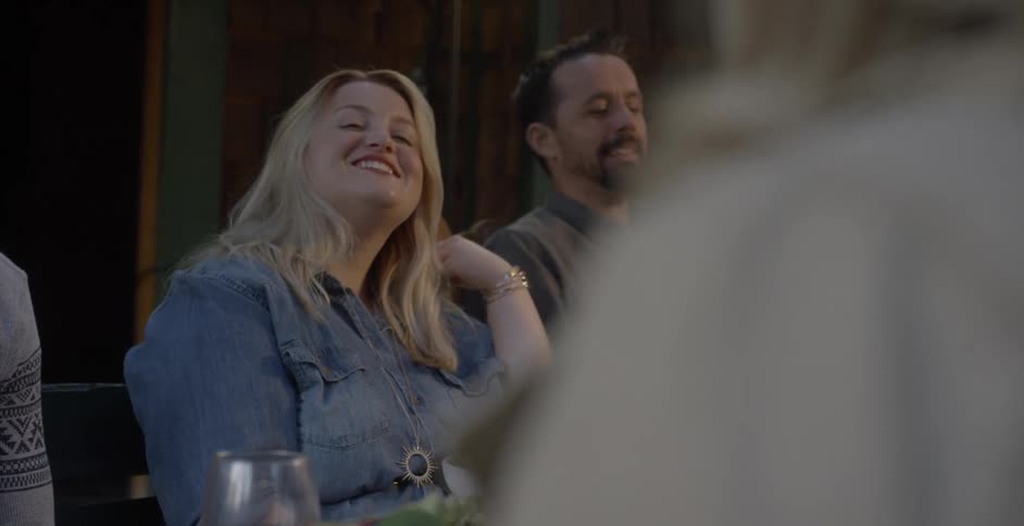 People laugh and talk at the dining table outside