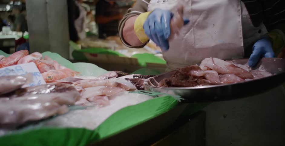 A woman piles raw seafood in a market