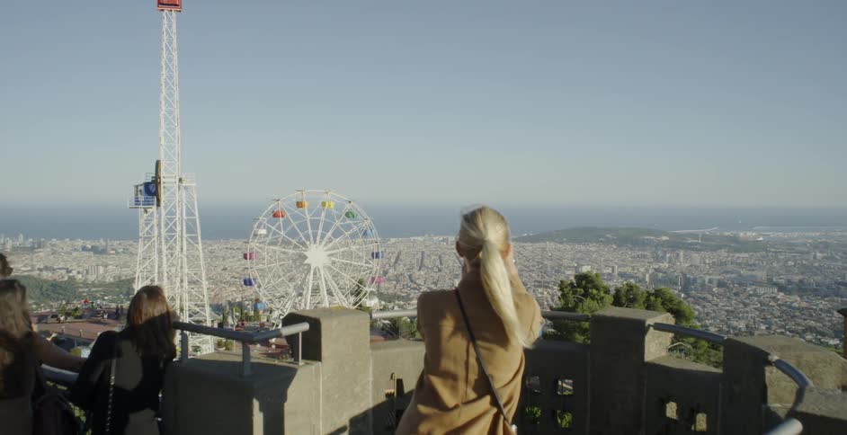 A woman photographs carnival rides from atop a building