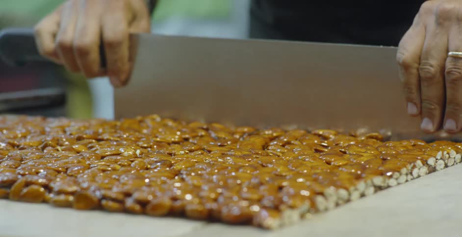 A man cuts up a sheet of candy