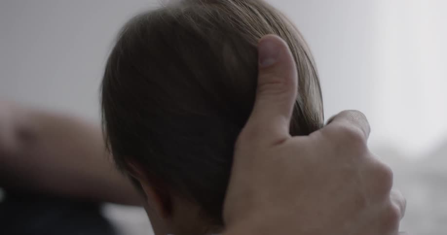 A man is rubbing the back of a baby's head
