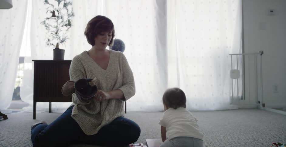 Woman uses a puppet while playing with a baby