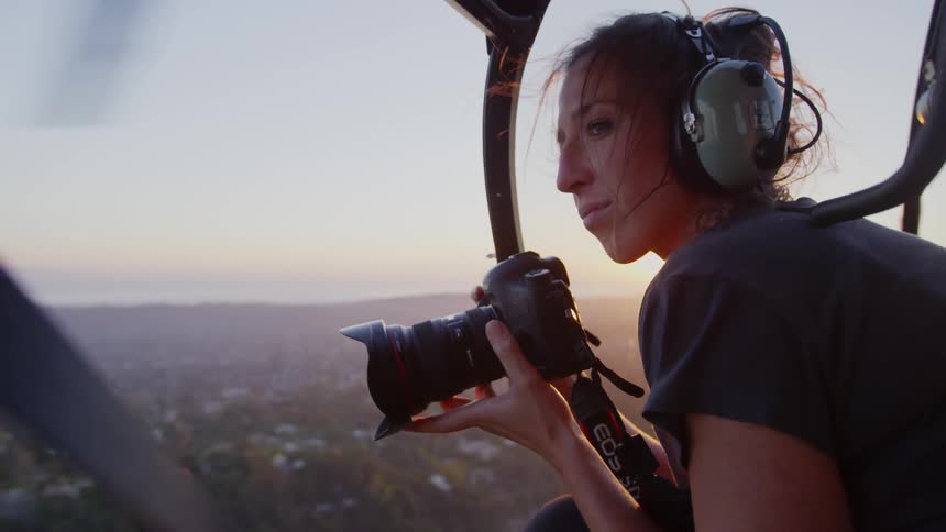 Woman taking photos from a helicopter as the sun sets