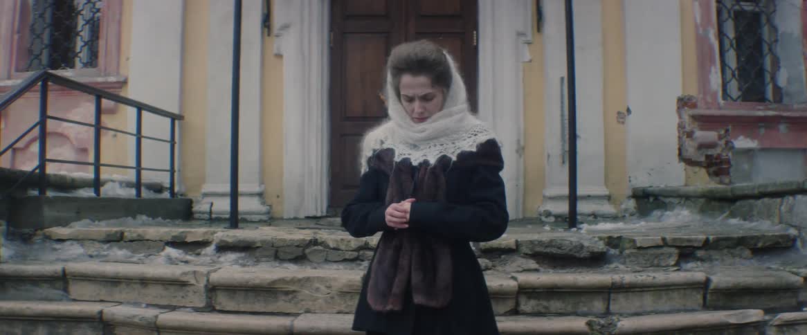 A woman stands outside of an old building