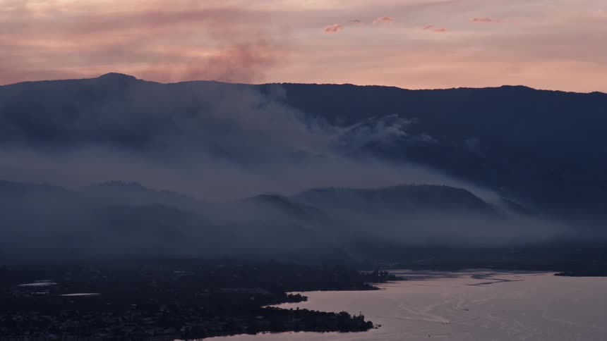 Smoke pours from the side of a mountain