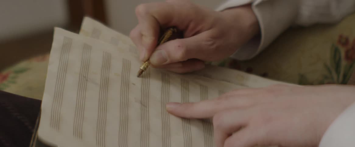 A composer writes on music sheets