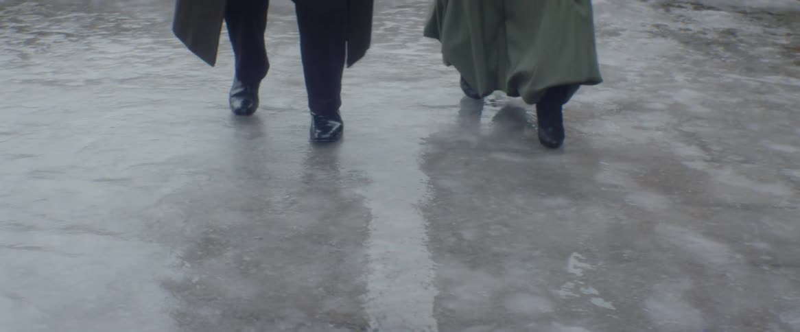 A man and woman walk and slide on ice
