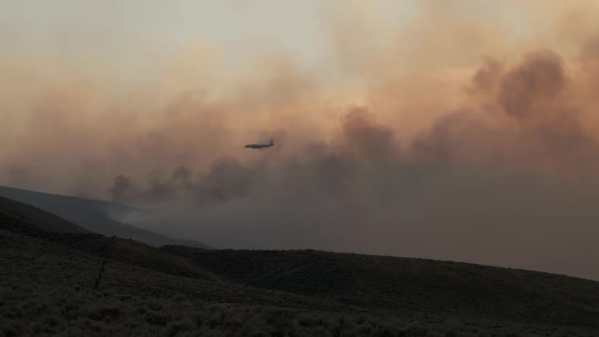 The plane flies over the burning field