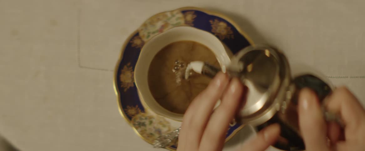 A woman pours cream into a cup of coffee
