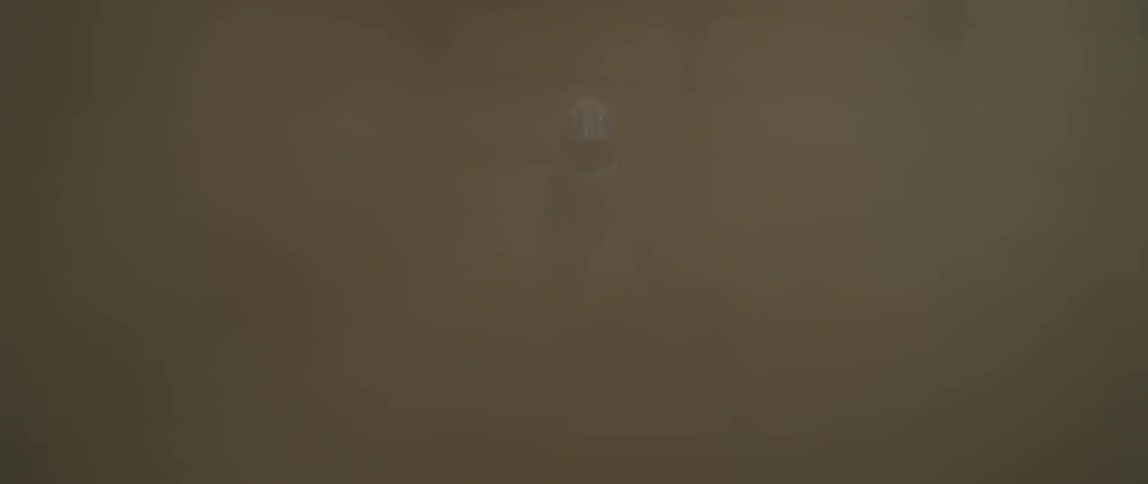 Man rides a dirt bike in circles spraying dirt inside a building