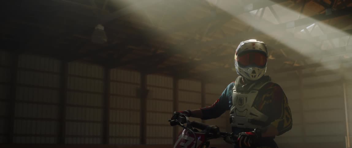 Misty breath is flowing from a motorcycle rider's helmet as he sits on it in daylight