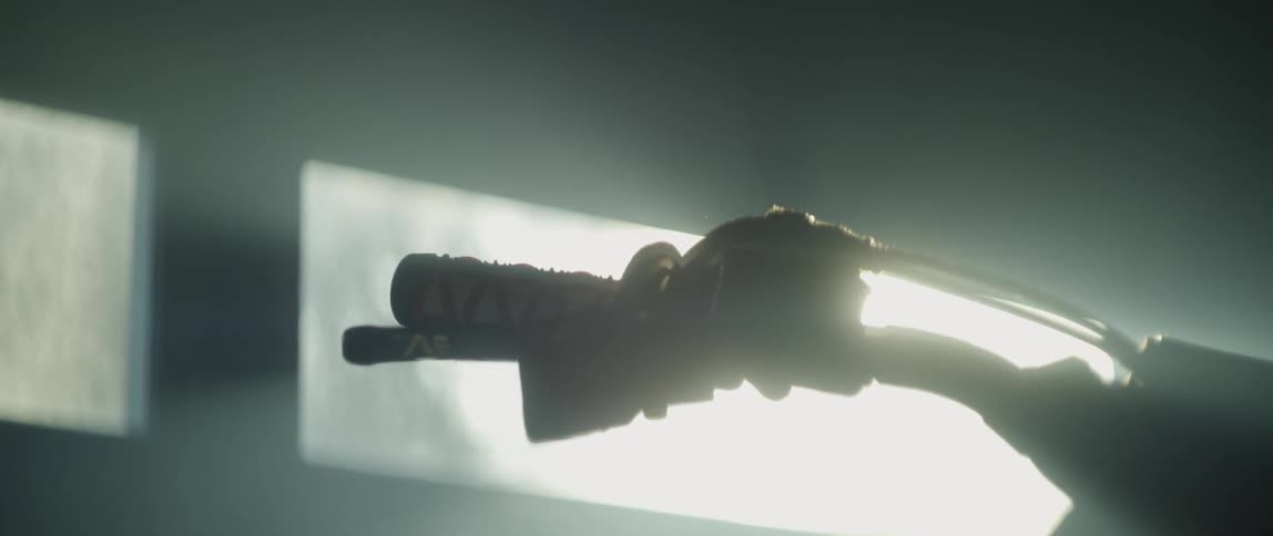 Sunlight shines on the handles of a dirt bike parked in a dusty garage