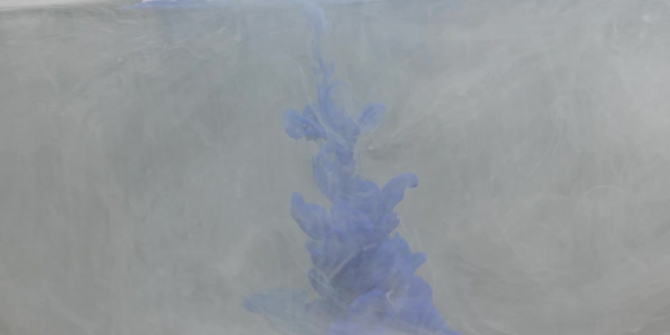 A cloud of purple colored dye is billowing and descending into an opaque liquid