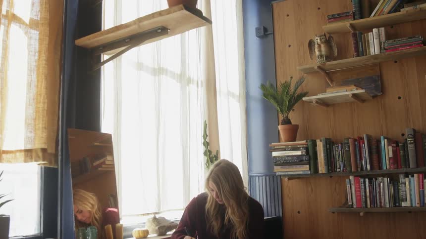 A woman writes at a small table