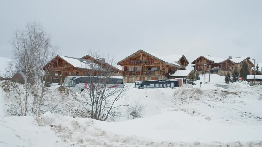 A bus is driving through a small snow covered village