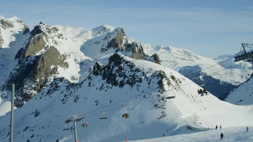 Ski lift carries people up and down a mountain while skiers ski below