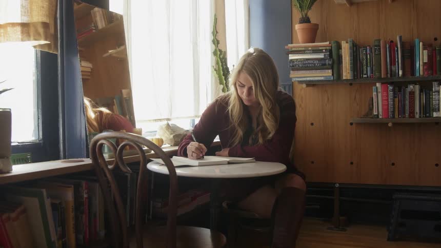 A woman writes at a small table