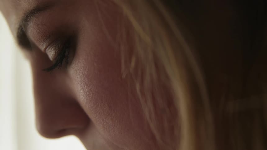 A woman is is opening her eyes as she concentrates while sitting indoors in daylight