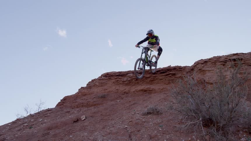 A dirt biker jumps and rides down a hill
