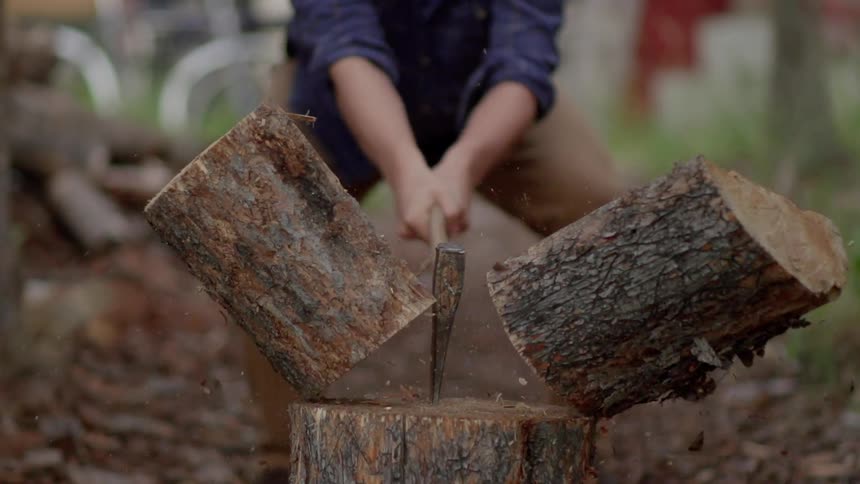 Man uses an ax to split a log in two