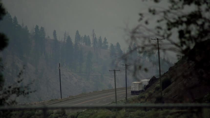 A truck is traveling on a mountain road on a windy day