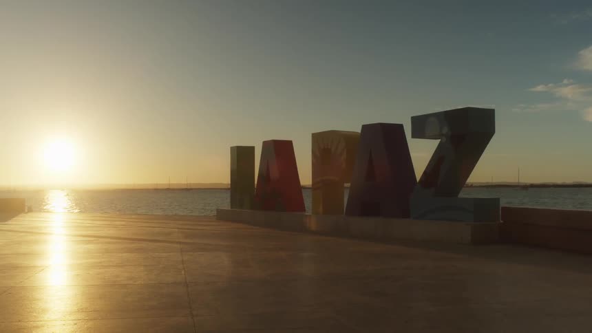 The la paz sign near the ocean at sunset