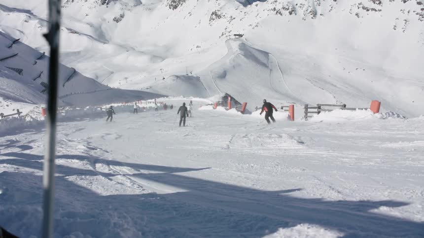 People skiing down a mountain ski slope on a sunny day