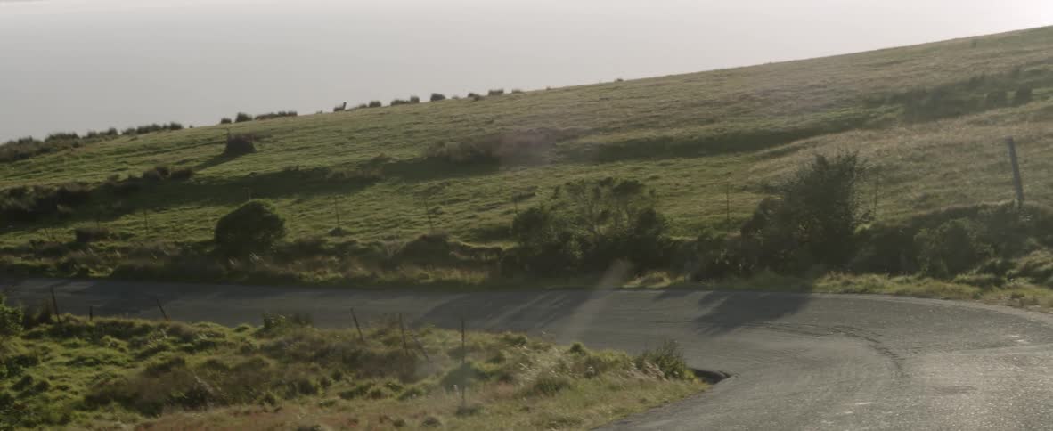 A road curves along a green hill