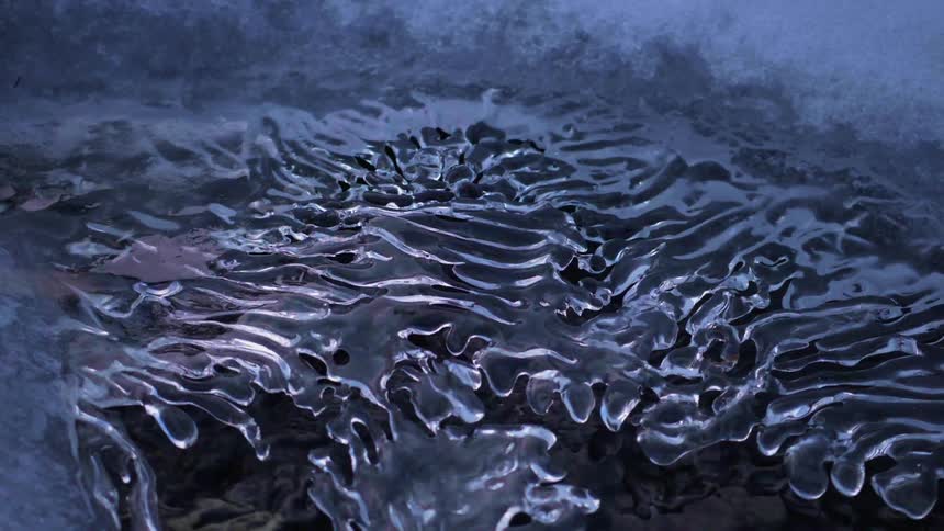 Water falls under thin frozen ice