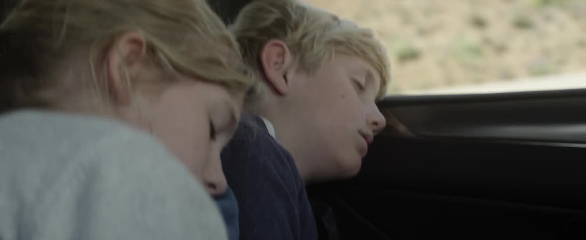 Girl sleeps on a boy's shoulder who is also sleeping in a car