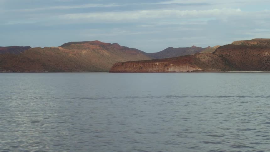 Brown hills beyond a beach on a cloudy day