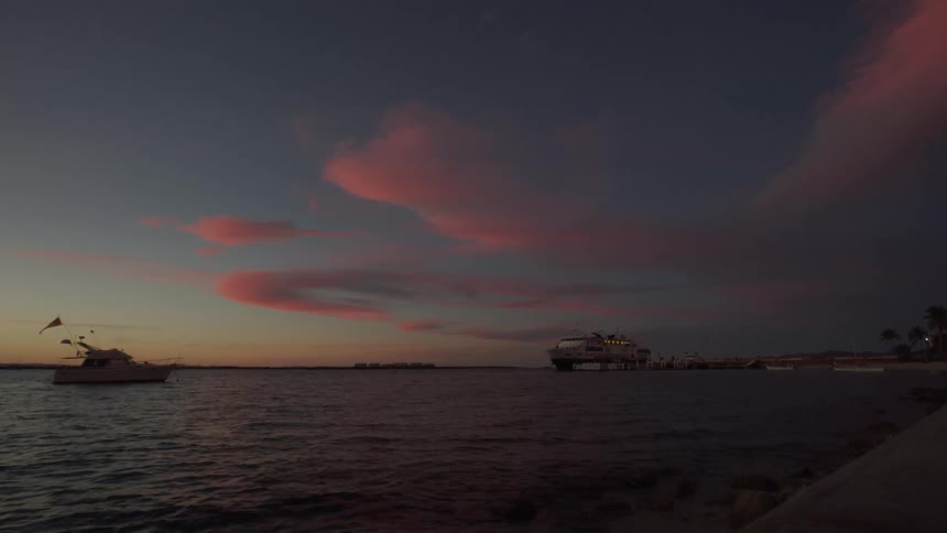 Boats float on the open water at sunset