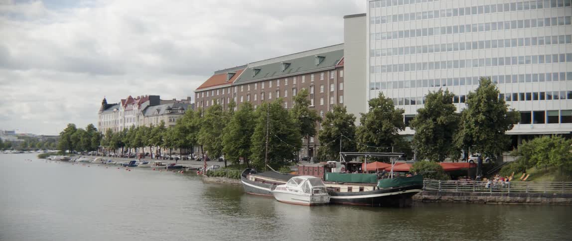 Small ships sit quietly next to a public concrete promenade in the afternoon.