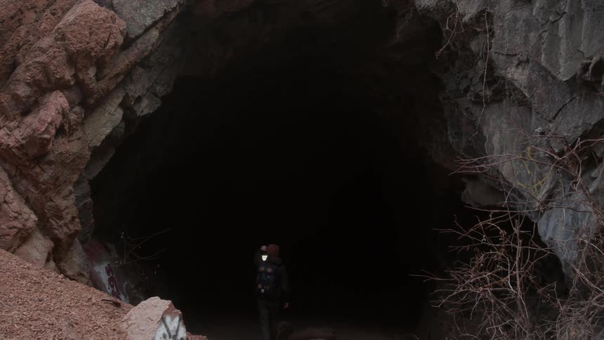 A man walks into a cave holding a lantern