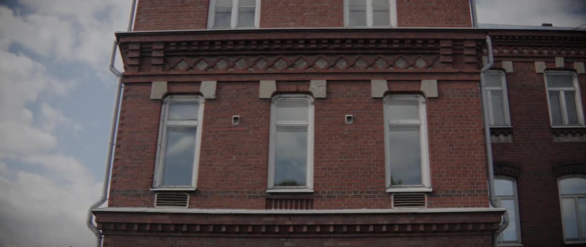 Three white framed windows line the upper floor of historic red brick architecture.