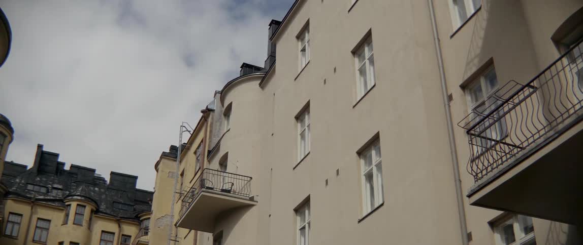 White clouds pass over a classic residential building with small metal balconies outdoors.