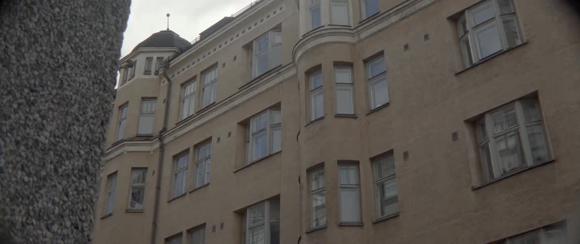 Vintage architecture features a curved corner tower and multiple rectangular glass windows outdoors