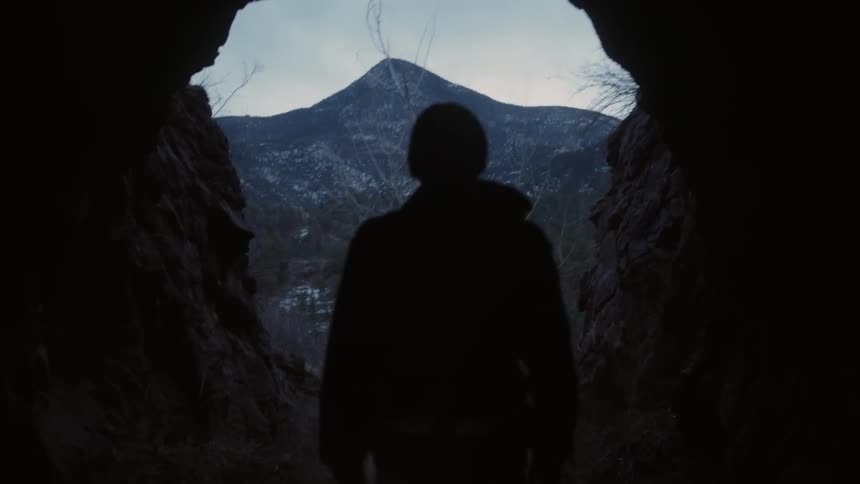 A man carrying a lantern walks out of a cave