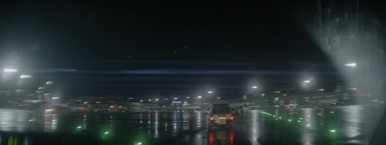 An airport vehicle is traveling across the tarmac at an airport at night