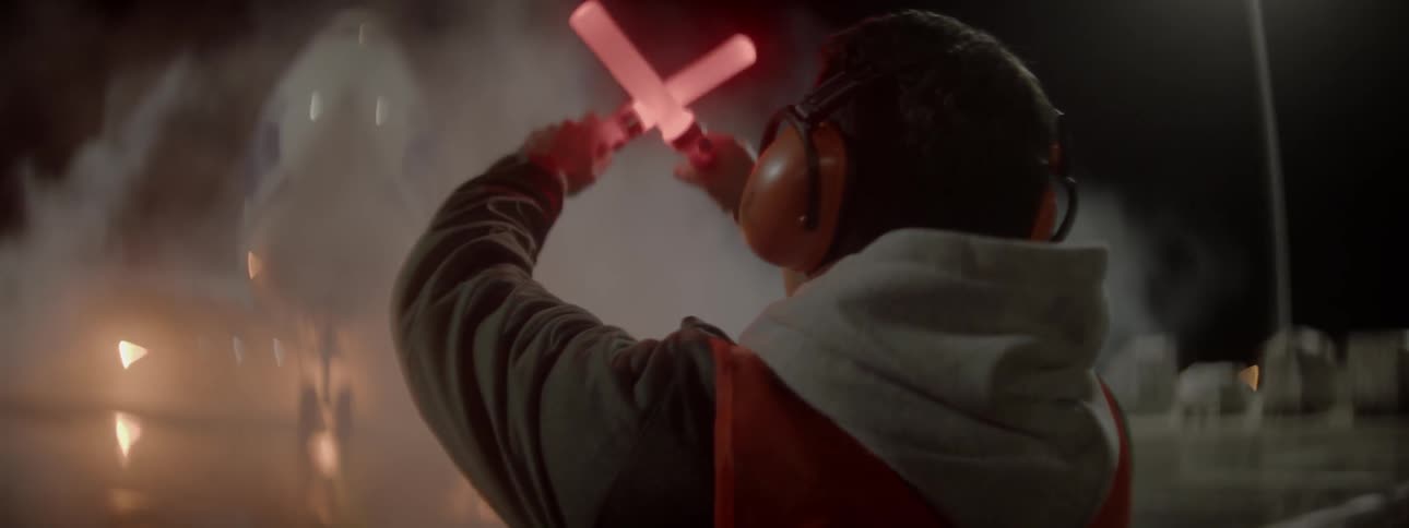 Man instructing a plane's movement at night using glow lights