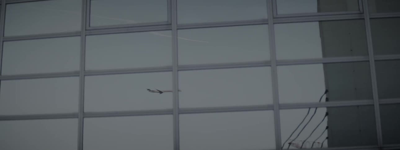 Reflection of an airplane off a large building with windows