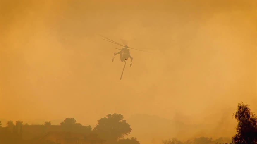 A helicopter flies over a forest fire