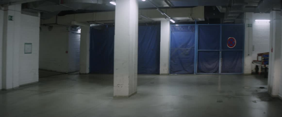A section of a parking garage is fenced off with blue tarp