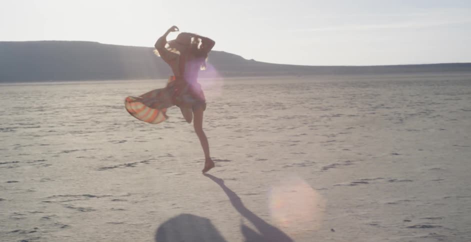 A woman dances outside under the sun