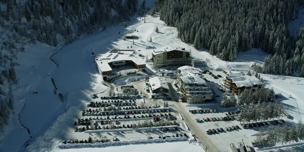 Buildings and a parking lot sit nestled in snowy mountains