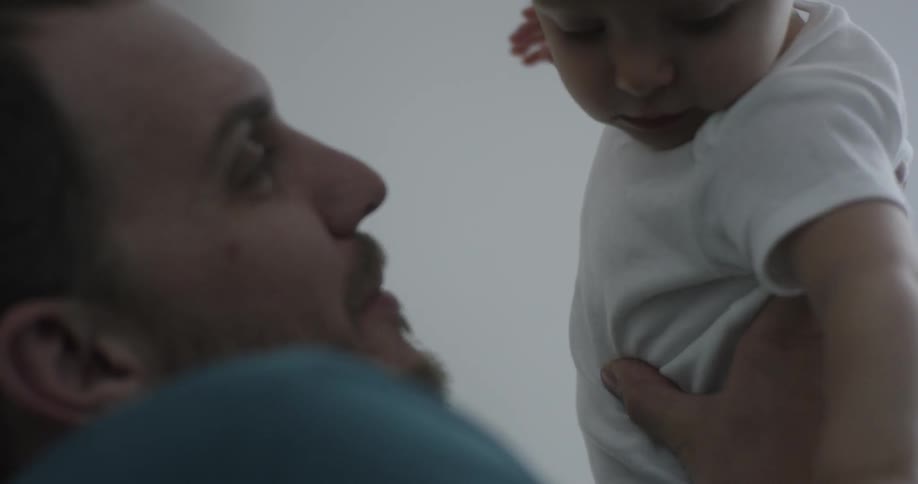A man raises a baby above his head smiling