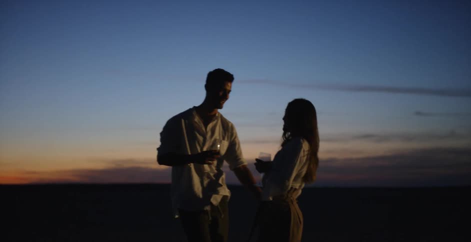 Man and woman dance outside at sunset