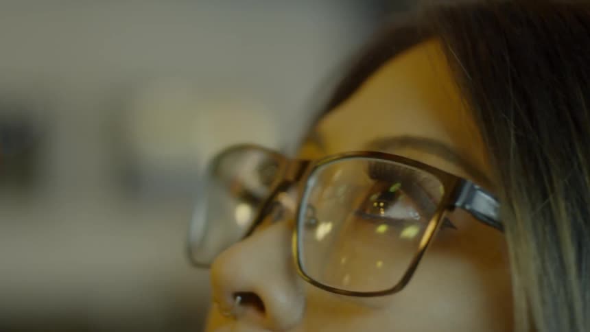 Woman wearing glasses looks up and light reflects off the glasses