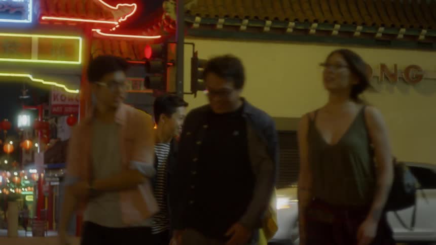 People cross a street in chinatown at night