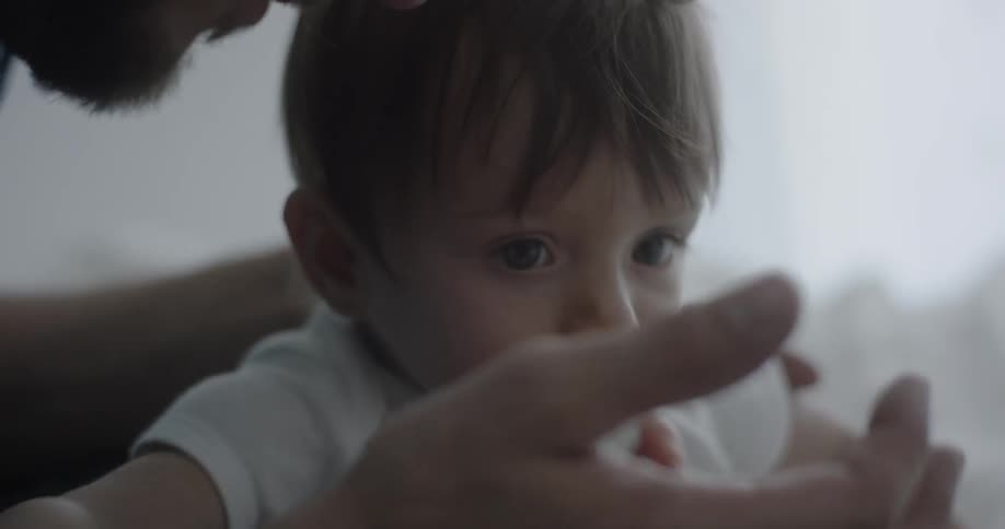 Man playing with baby's foot in dim room